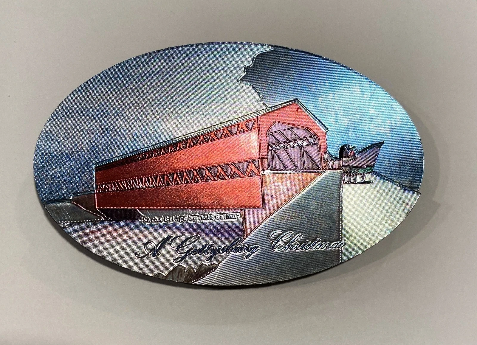 Golden Christmas ornament featuring a red covered bridge