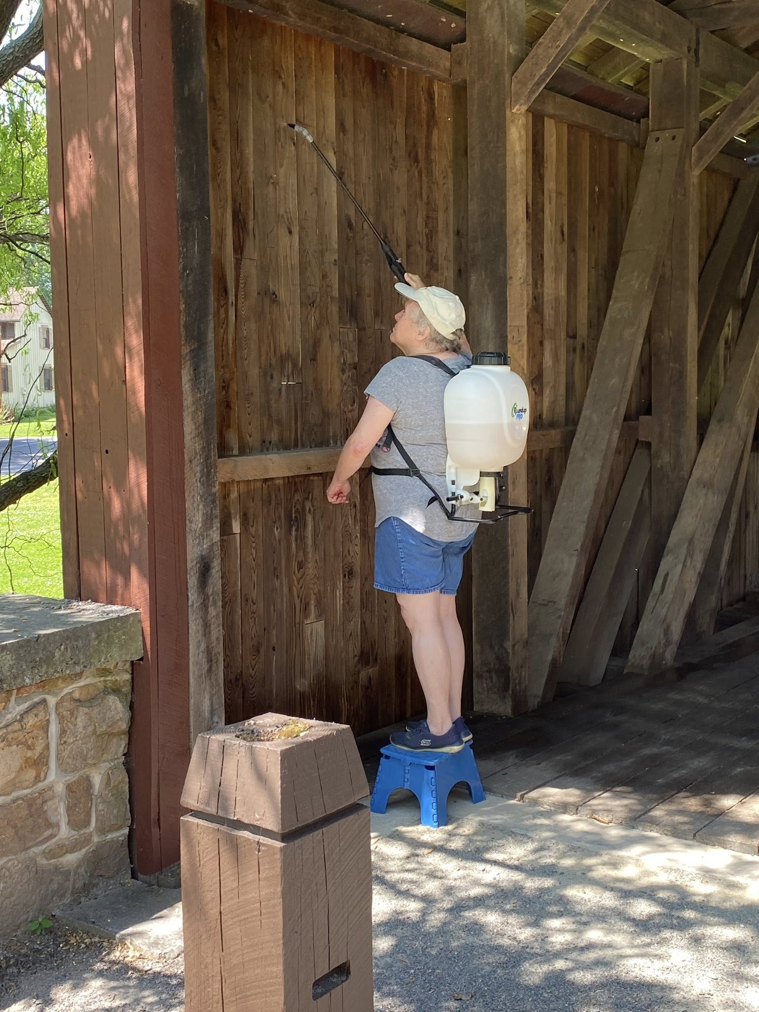 Volunteer spraying NoChar fire retardant on the siding of Fort Hunter Covered Bridge