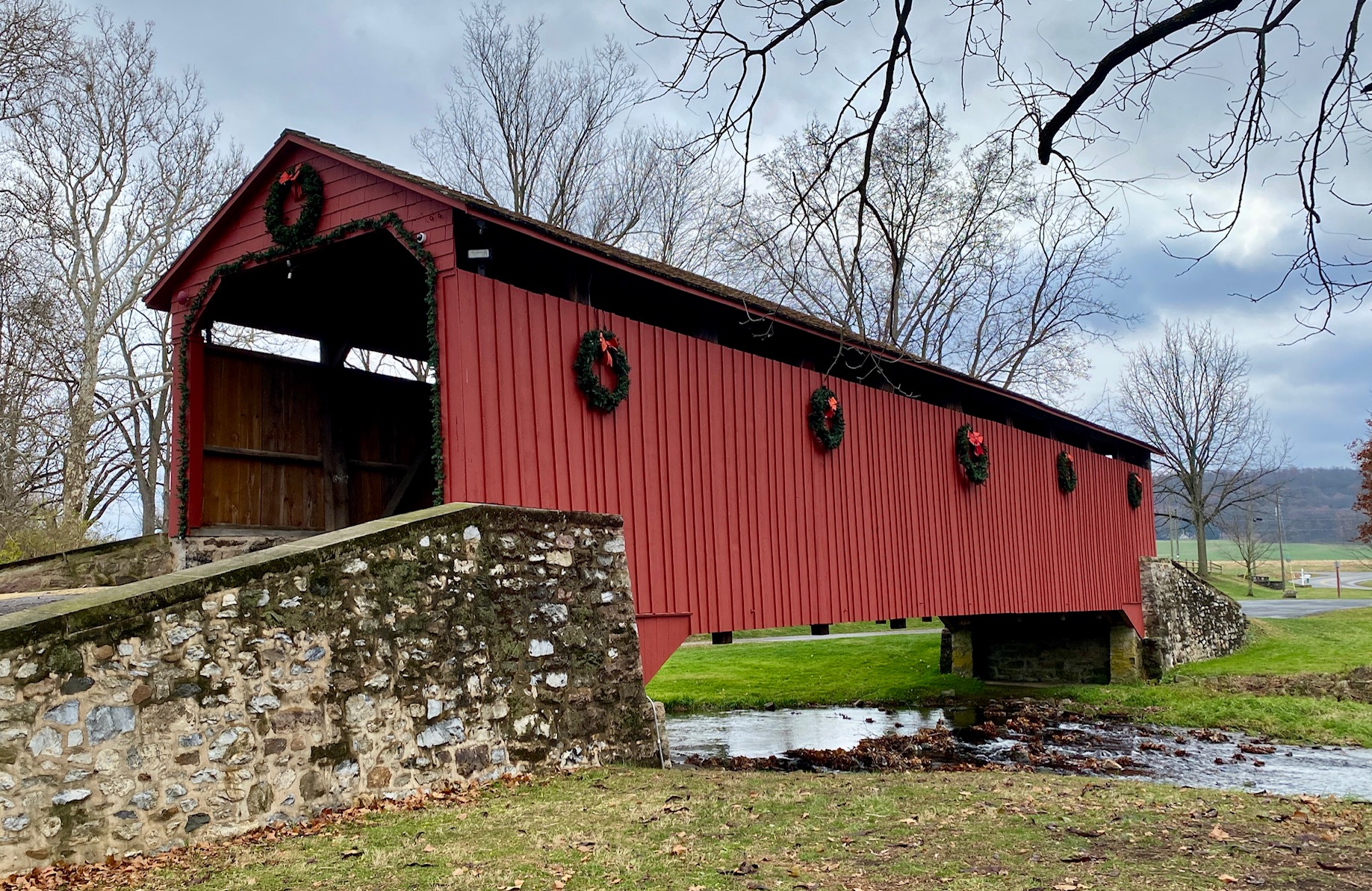 Exterior view of Poole Forge Covered Bridge in Lancaster County decorated with Christmas wreaths along the red siding